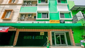 A building with a green and white facade, a sign for "Grand & Azilah," and a "Spot On" sign above the entrance. - Hotel O Grand Azizah (Makassar)