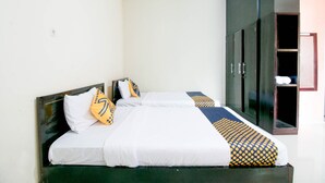 A double bed with white bedding and patterned pillows, a dark headboard, and a wardrobe with a mirror. - Hotel O Grand Azizah (Makassar)