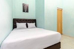 A neatly made bed with a tufted headboard in a room with light blue walls and a small door. - OYO Life 2158 Arista Residence Syariah (Medan)