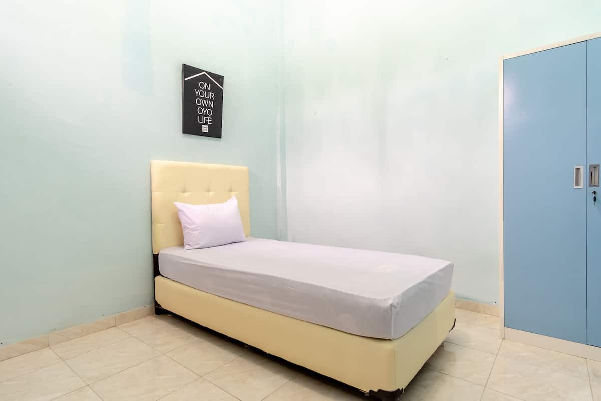 A single bed with a headboard and a mattress, a wardrobe with two doors, and a wall-mounted sign.