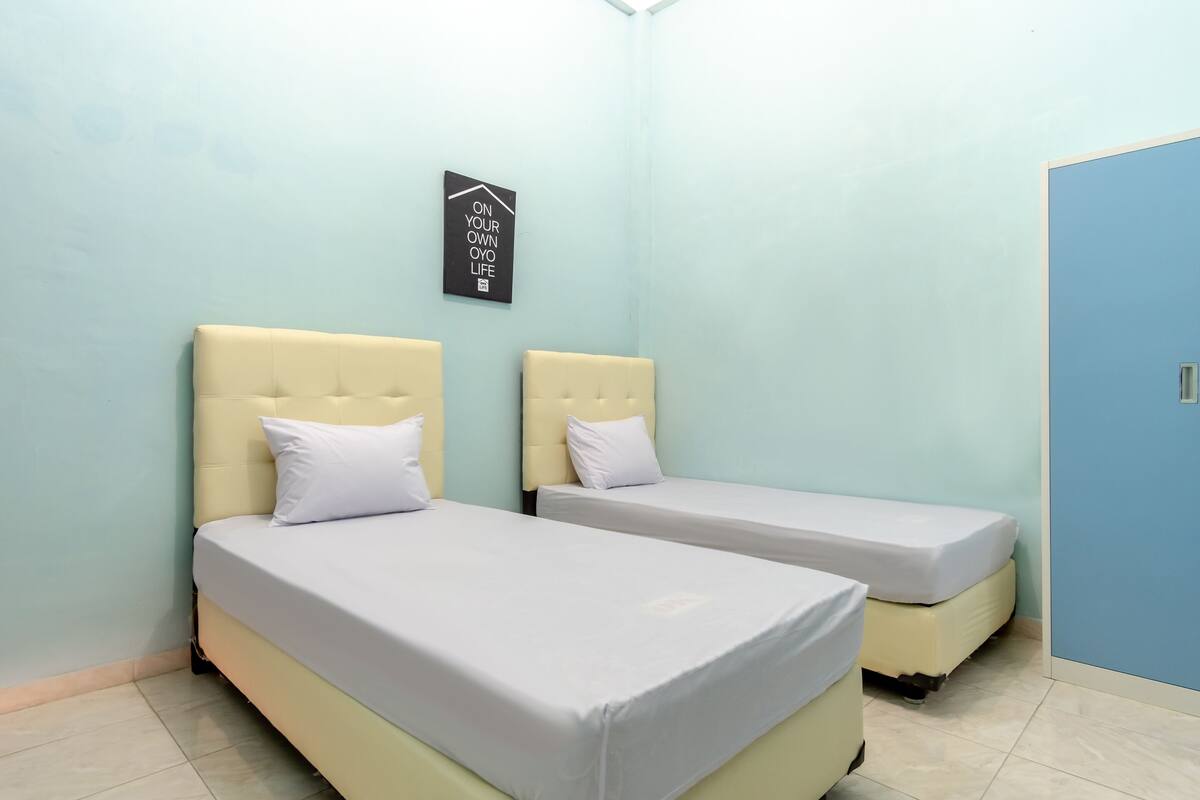A room with two beds, light blue walls, and a door.