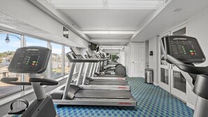 A gym with treadmills and elliptical machines, a patterned floor, and large windows. - 7th Floor Windy Hill Condo. Fitness Room, Pools, Wifi | Windy Hill Dunes - 704 (North Myrtle Beach)