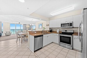 A modern kitchen with white cabinets, stainless steel appliances, and a large island with a dishwasher. - 7th Floor Windy Hill Condo. Fitness Room, Pools, Wifi | Windy Hill Dunes - 704 (North Myrtle Beach)