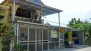 A two-story building with a balcony, a covered entrance, and several potted plants. - SPOT ON 1854 Sepinggan Asri Syariah Guesthouse (Balikpapan)