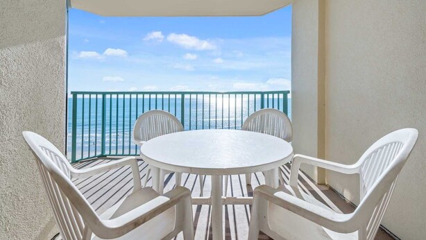 A balcony with a round table and four chairs, overlooking a body of water. - Nautical Oceanfront Condo, Outdoor Covered Heated Pool | Pinnacle - 802 (North Myrtle Beach)