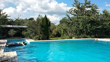 Una piscina al aire libre de temporada, sombrillas