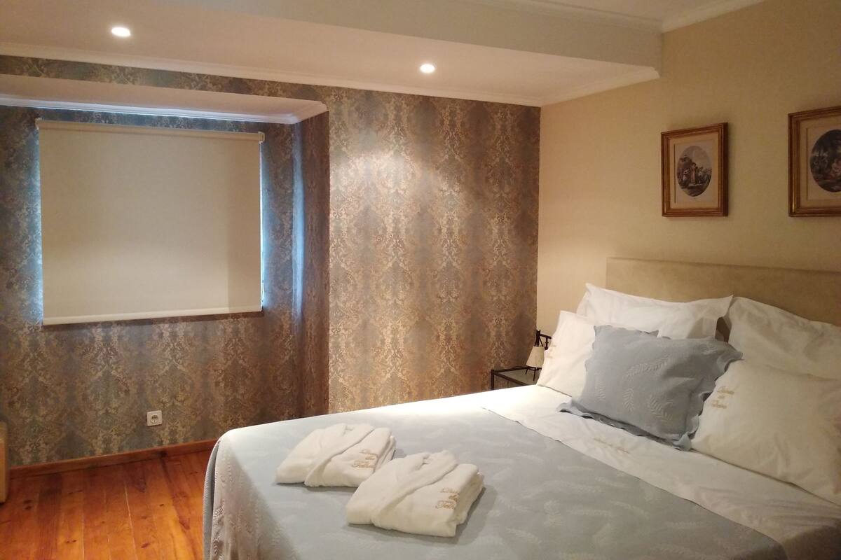 Et hotelværelse med en stor seng, to puder, et natbord og et vindue med udsigt.