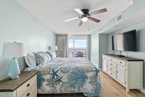 A bedroom with a bed, a ceiling fan, a TV, and a balcony with a view. - Modern Condo, Free Wifi, Indoor and Outdoor Pools | South Shore Villas - 604 (North Myrtle Beach)