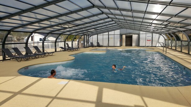 An indoor swimming pool with a glass ceiling, sun loungers, and a lifeguard stand. - Camping - Caravaning les Cerisiers Berck sur Mer (Verton)