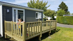 A wooden deck attached to a grey mobile home with a window and a door. - Camping - Caravaning les Cerisiers Berck sur Mer (Verton)