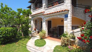 A stone building with a garden entrance, outdoor seating, and a sign indicating it is a guesthouse.