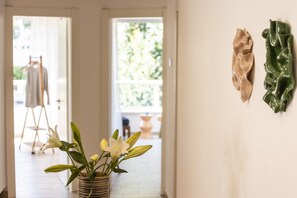 A hallway with a potted plant, a clothing rack, and wall-mounted decorations.