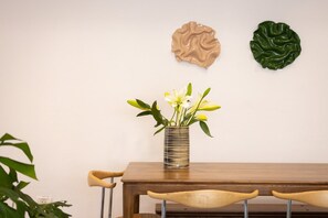 A dining table with a vase of flowers, two chairs, and two wall art pieces. - 3BR + 3 Baths near Gordon Beach by SeaNRent (Tel Aviv)