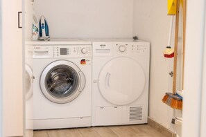 A laundry room with a Bosch and a NEON washing machine, a broom, and a mop.