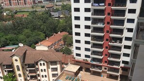 Un immeuble de grande hauteur doté de nombreux balcons, d’une piscine et d’un jardin bien entretenu.