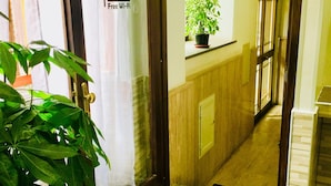 Un pasillo con puerta de madera, una planta en maceta y suelo de baldosas.