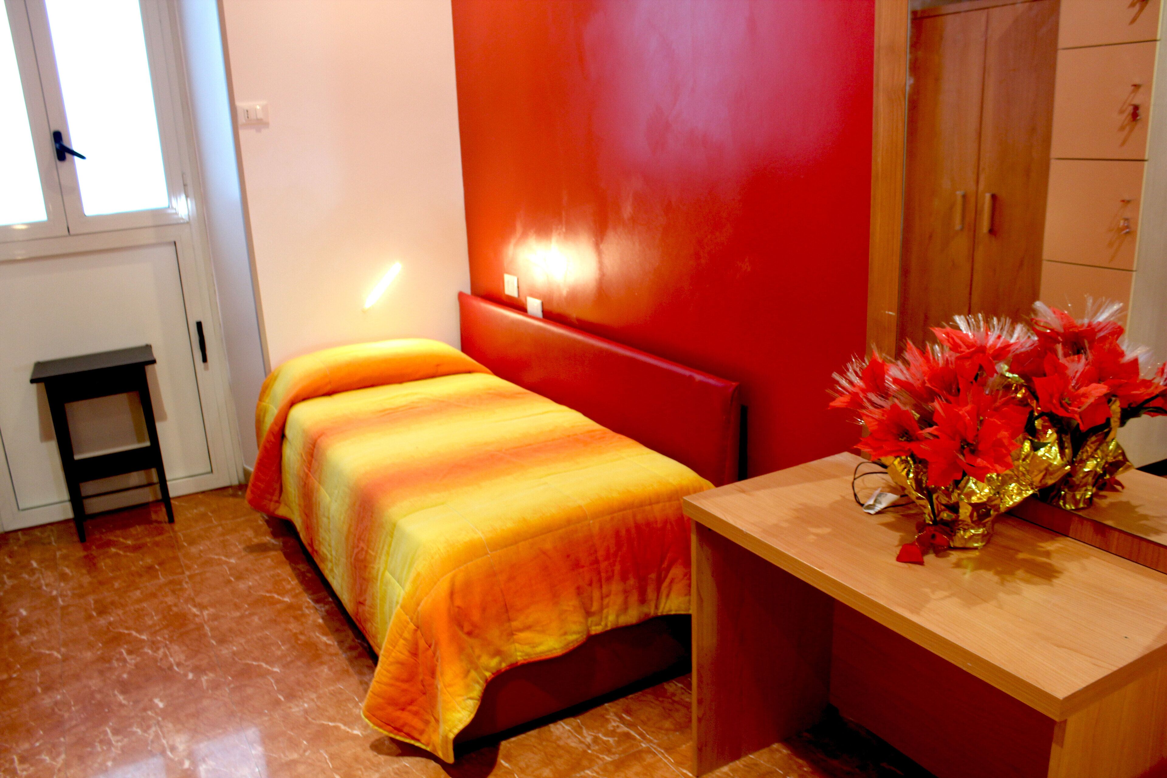 Um quarto com uma cama, uma mesinha e um armário.