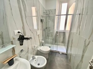 A bathroom with a glass-enclosed shower, a bidet, and a sink. - Residenza  Giustiniani (Rome)