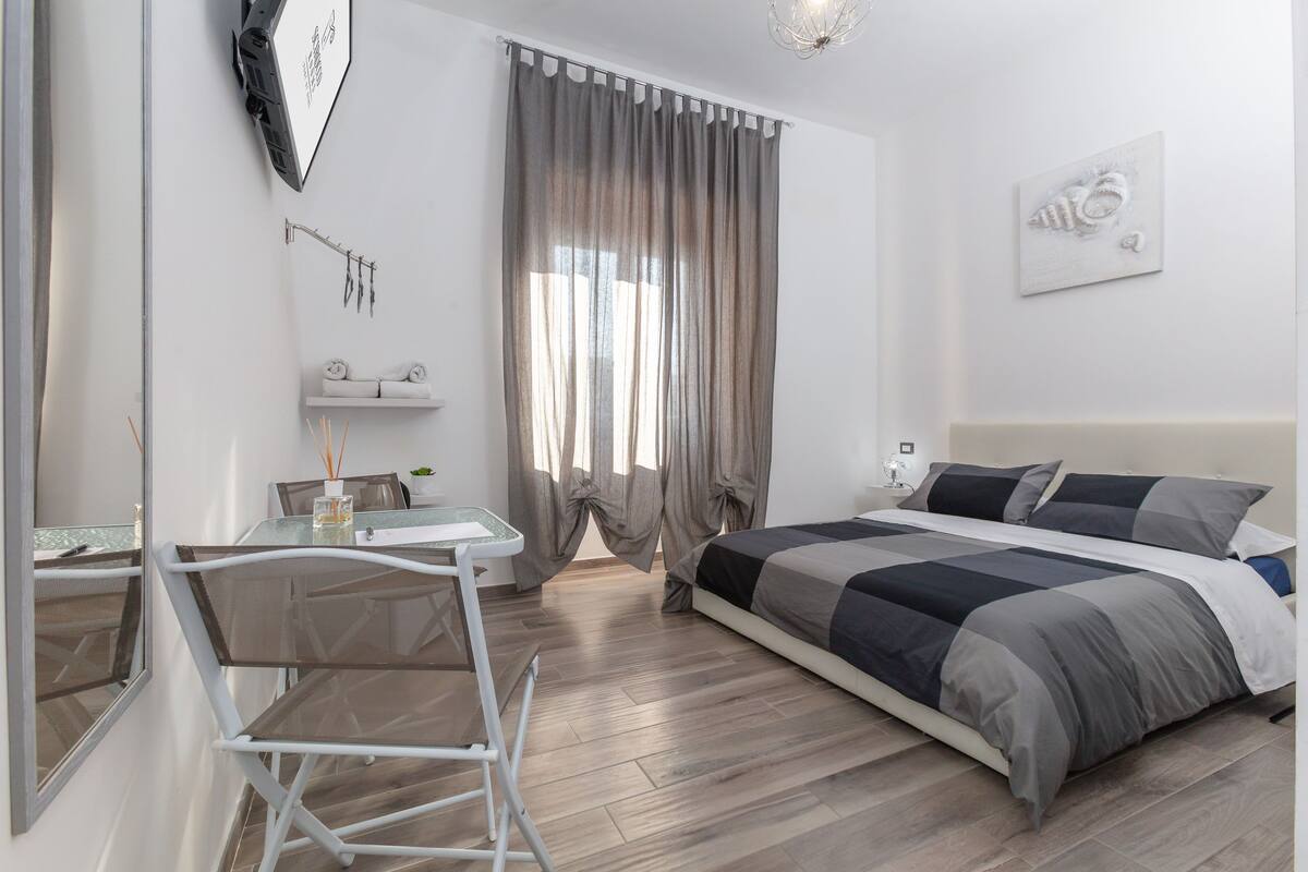 A bedroom with a bed, a desk, and a chair.
