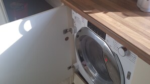 Una lavadora de carga frontal en un cuarto de lavado, con mostrador de madera y salpicadero de azulejos.