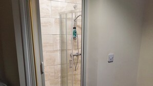 Un baño con ducha, inodoro y un armario de madera.