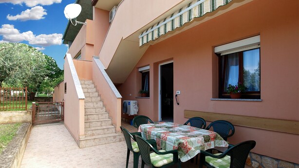 An outdoor patio with a table and chairs, a staircase, and a building with a door and windows. - Apartment 1858/22636 (Istria - Valbandon), 1000m from the beach (Valbandon)