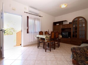 A dining area with a table and chairs, a television, and wooden cabinets. - Apartment 1858/22636 (Istria - Valbandon), 1000m from the beach (Valbandon)