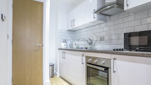 A modern kitchen with white cabinets, a stainless steel oven, and a microwave. - Tudors eSuites Birmingham Canalside Apartments (Birmingham)