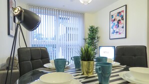 A dining area with a checkered table, chairs, and a potted plant. - Tudors eSuites Birmingham Canalside with Gated Parking (Birmingham)
