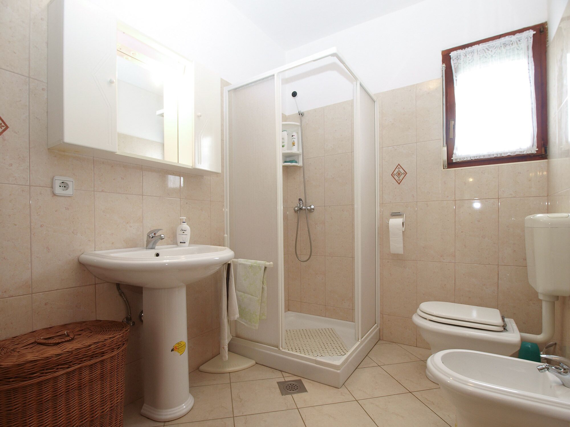 Un baño con ducha, lavabo, inodoro y un espejo grande.