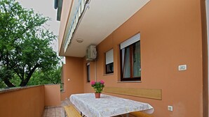 A balcony with a table and benches, a potted plant, and a window with blinds. - Apartment 1858/22637 (Istria - Valbandon), 1000m from the beach (Valbandon)