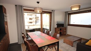 Una sala de estar moderna con comedor, televisor y balcón con vistas.