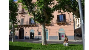 A building with a classical architectural style, featuring arched doorways and a central entrance. - Agorà Panoramic Rooms (Sciacca)