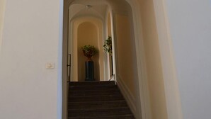 A grand staircase with a decorative ceiling medallion and a potted plant at the top. - Agorà Panoramic Rooms (Sciacca)