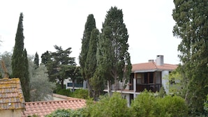 A residential building with a tiled roof, surrounded by tall trees and greenery. - Cozy Apartment with Parking, 100m from Beach - Argelès-sur-Mer (Argelès-sur-Mer)
