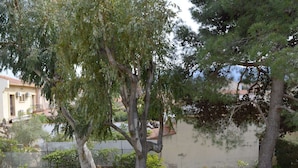 A courtyard with trees, a building with a tiled roof, and a low wall. - Cozy Apartment with Parking, 100m from Beach - Argelès-sur-Mer (Argelès-sur-Mer)