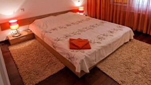 Un lit bien fait, recouvert d’une couvre-lit à motifs floraux, avec deux lampes de chevet, une table de chevet et un tableau encadré accroché au mur.