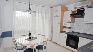 A compact kitchen with white cabinets, a microwave, and a stove. - Apartments Spommy (Crikvenica)