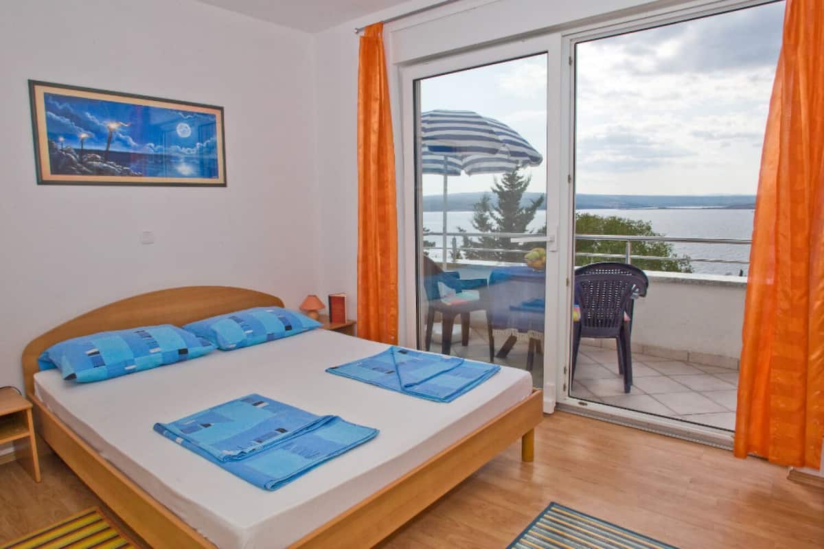 Um quarto com cama, uma pintura do céu noturno e varanda com vista para o mar.