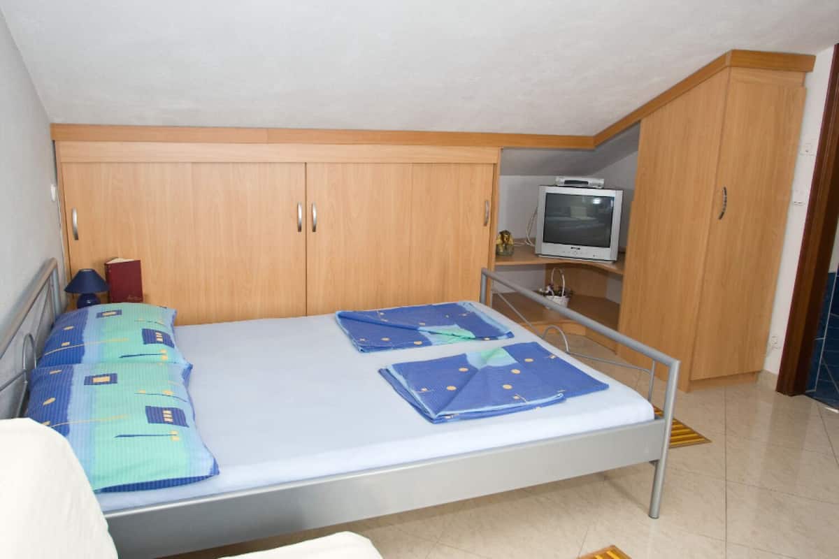 Quarto com uma cama, guarda-roupa de madeira e uma televisão.