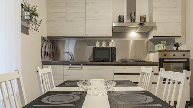 Une cuisine moderne équipée d’une table à manger, de chaises, d’un four à micro-ondes et d’une cuisinière à gaz.