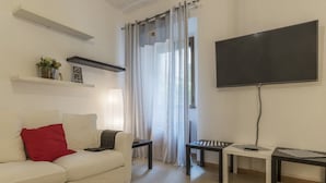 Un salon avec un canapé, un téléviseur et deux tables d’appoint.