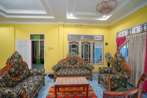 A room with a yellow wall, a wooden floor, a sofa, a table, and a chair.