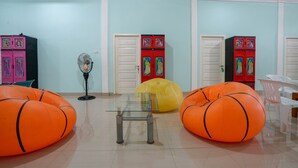 A room with teal walls, two white doors, a glass table, and orange bean bags.