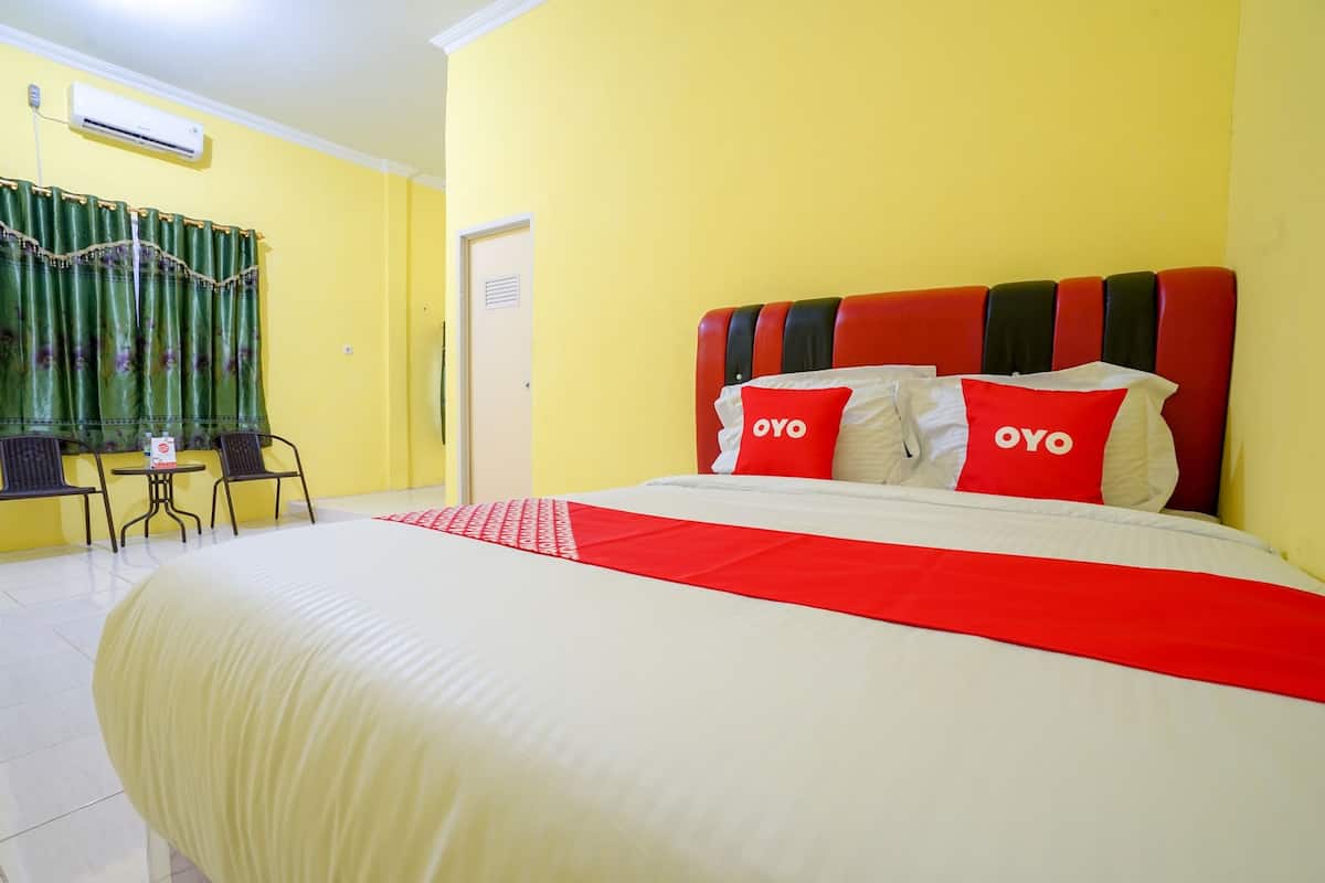 Une chambre d’hôtel avec un lit, une table, des chaises et un rideau.
