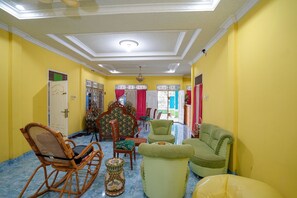 A room with yellow walls, a ceiling fan, and a variety of seating including a rocking chair, armchairs, and a sofa. - OYO 1991 Alam Lestari Homestay (Palembang)