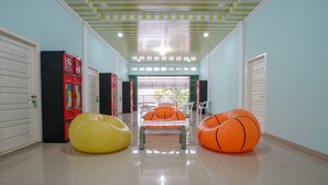 A hallway with a green striped ceiling, white doors, and colorful bean bag chairs.