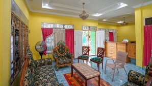 A living room with patterned sofas, a wooden coffee table, and a fan.