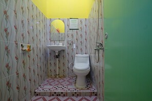 A bathroom with a toilet, sink, and shower. The walls have a floral tile pattern, and there is a yellow ceiling. - OYO 1991 Alam Lestari Homestay (Palembang)