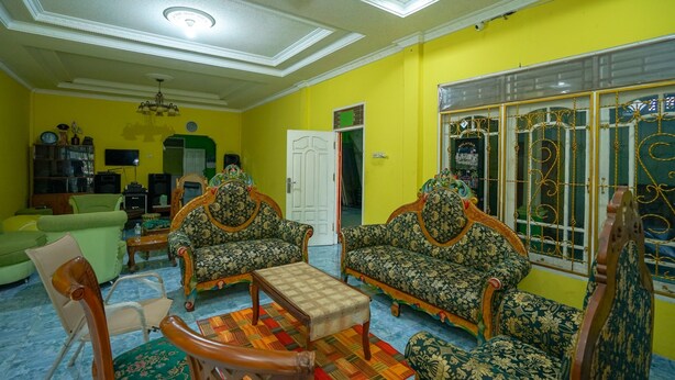 A living room with two ornate sofas, a wooden coffee table, and a green armchair.